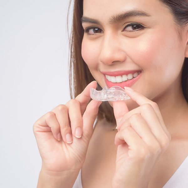 young-smiling-woman-holding-invisalign-braces-over-2023-05-16-16-24-54-utc (1)